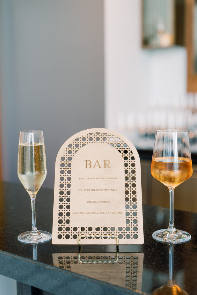 Laser cut wooden bar signage between two wine glasses.