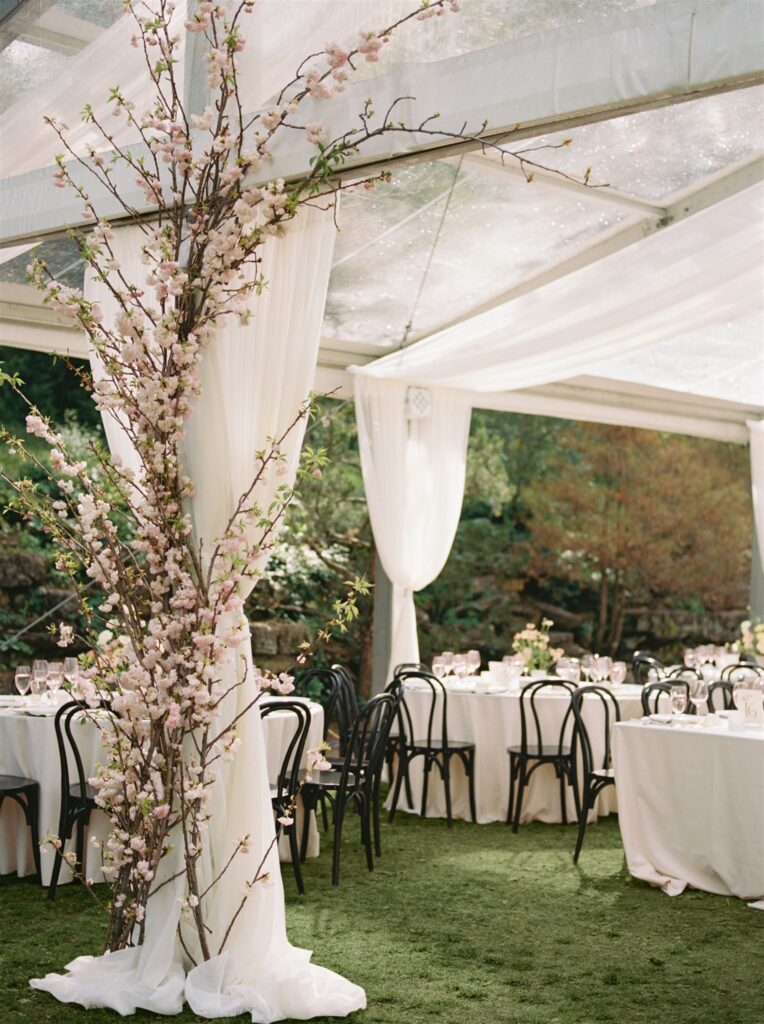 Outdoor reception tent and tables with tablescapes and floral decor.