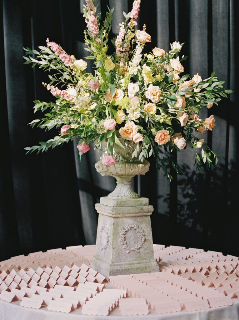 Escort card displayed on round lined table topped with florals.