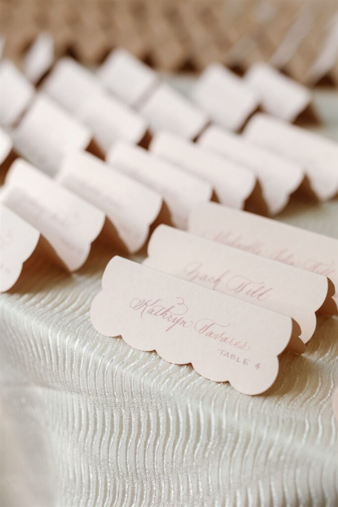 Scalloped escort cards in dusty rose.