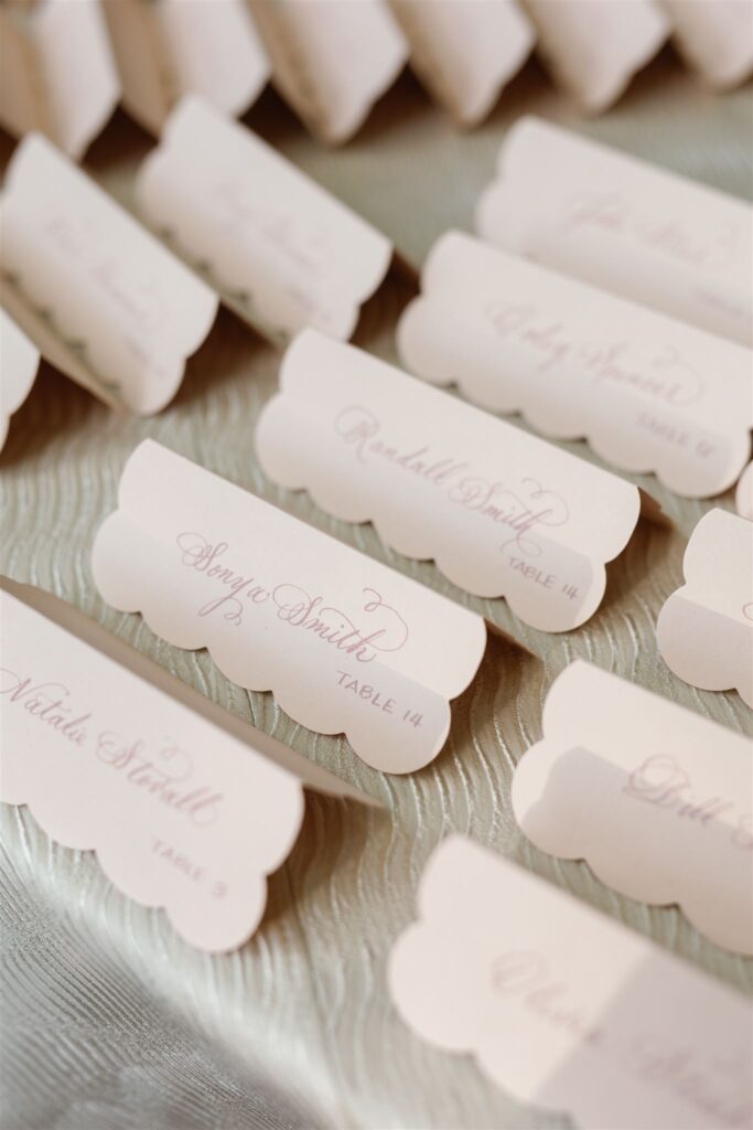 Scalloped escort cards in dusty rose.