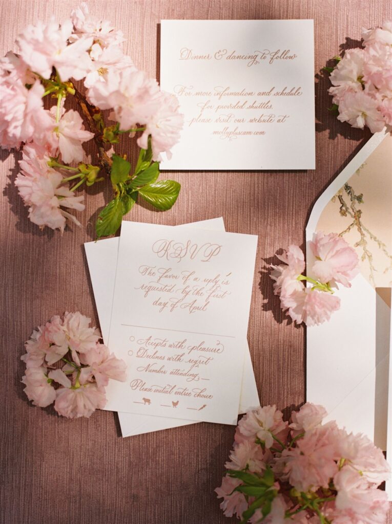 Flat lay of invitation suite boasting florals and full spot calligraphy.