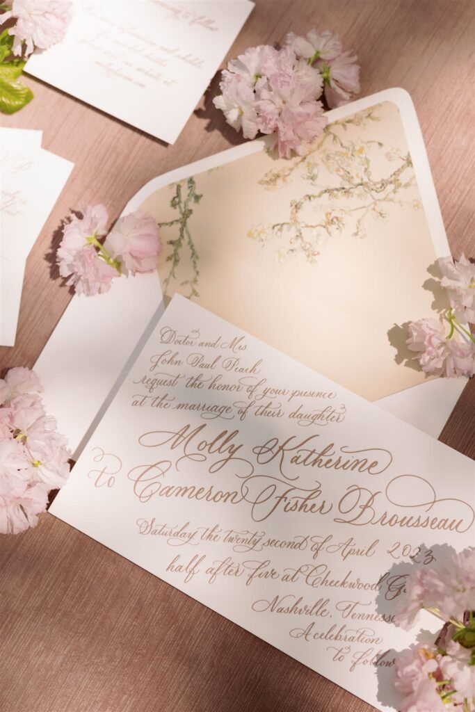 Flat lay of invitation suite boasting florals and full spot calligraphy.