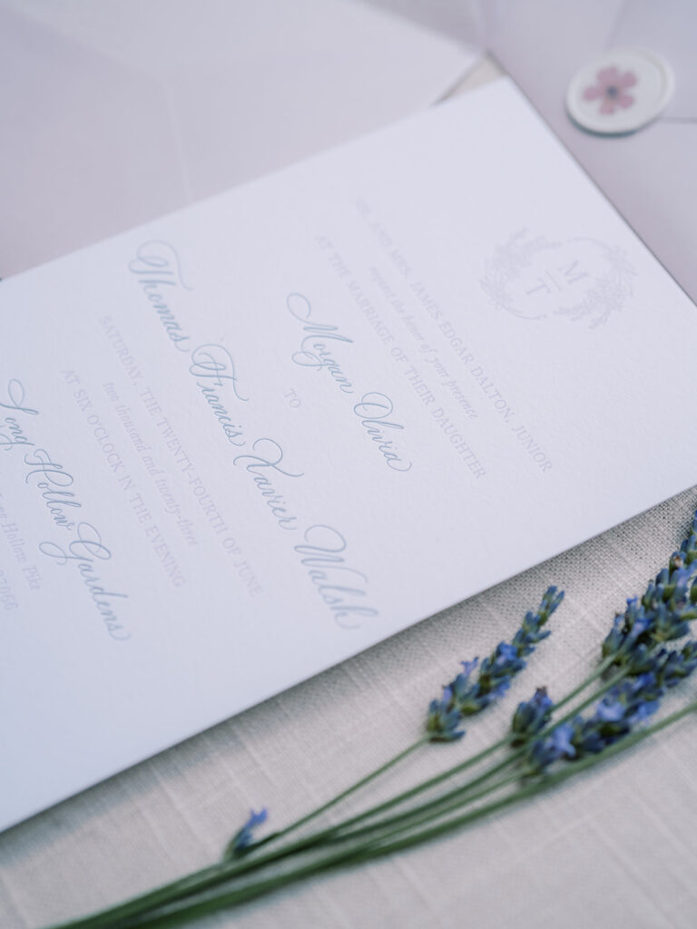 Invitation with lavender flowers beside it.
