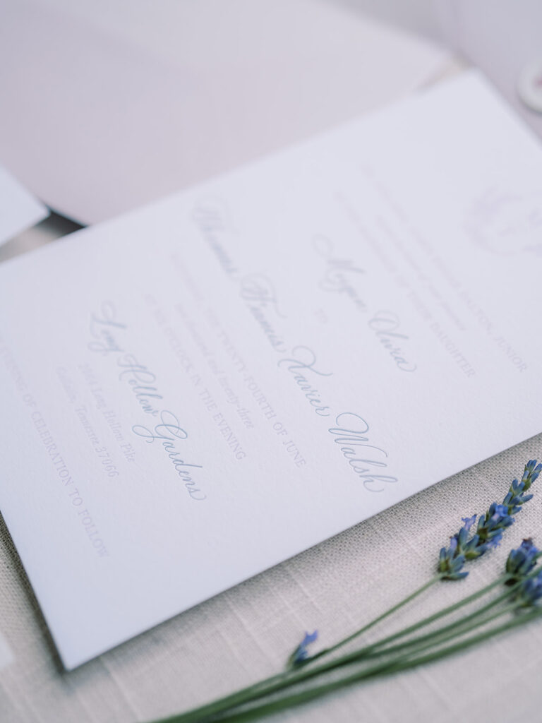 Invitation with lavender flowers beside it.