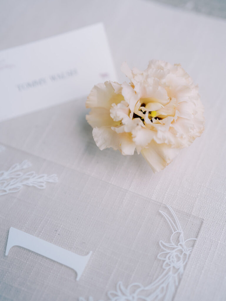 Frosted acrylic table number sign and place card styled with a flower.