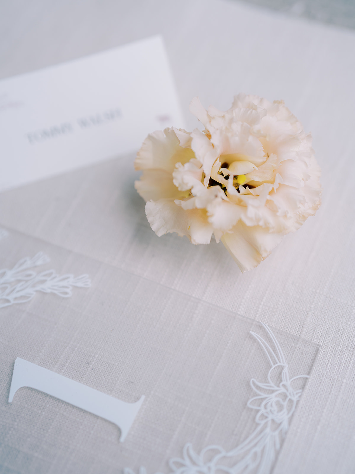 Frosted acrylic table number sign and place card styled with a flower.