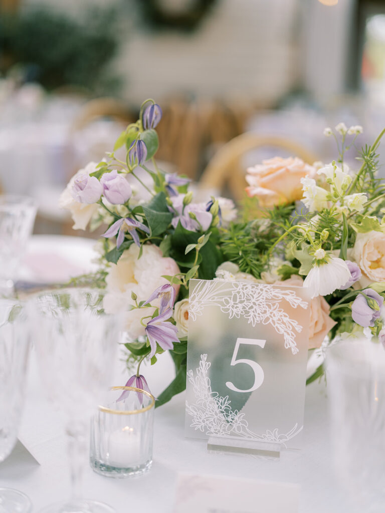 Floral arrangement on formal reception table setting with frosted acrylic table number in front.