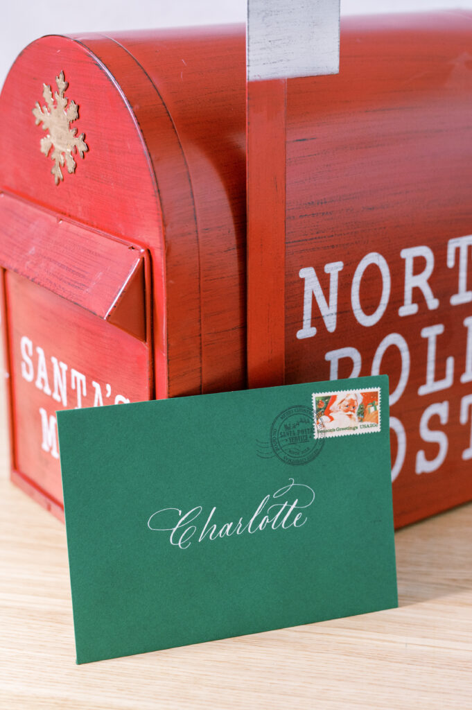 Green envelope with calligraphy and vintage holiday postage inside red mailbox