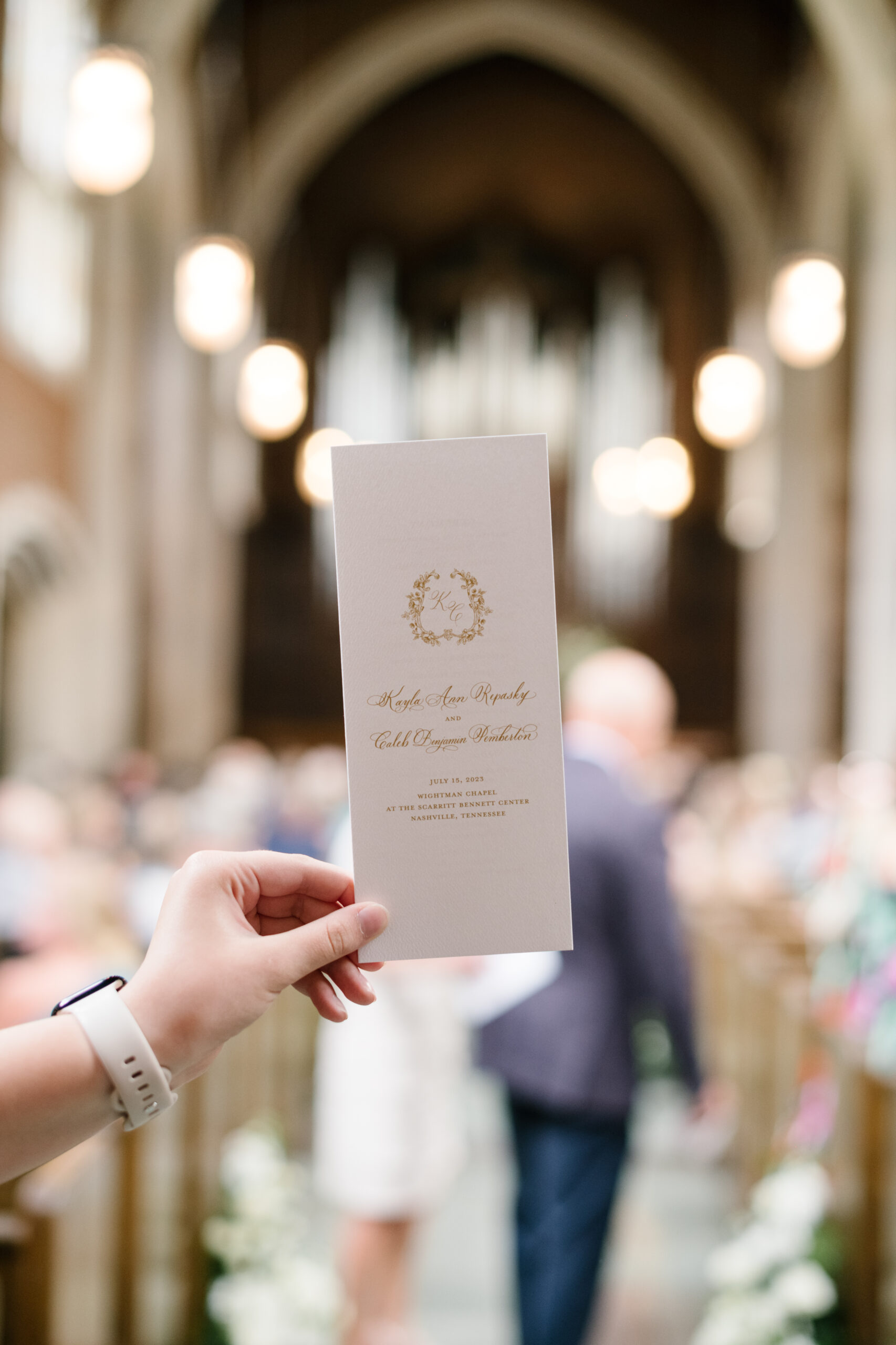 Hand holding up ceremony program created by Nashville calligraphy studio. 