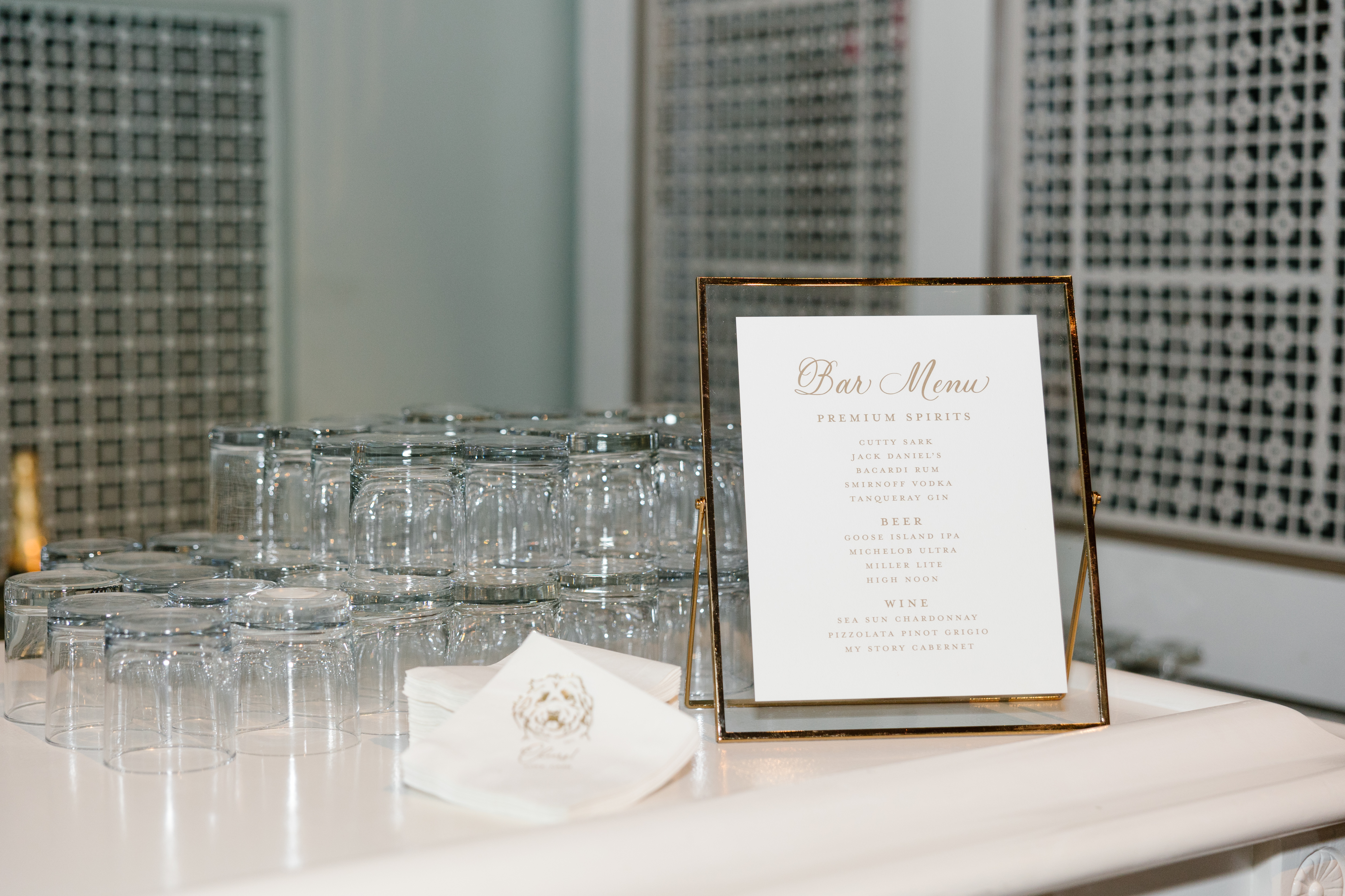 Bar menu, cocktail napkins and glasses on a counter top.