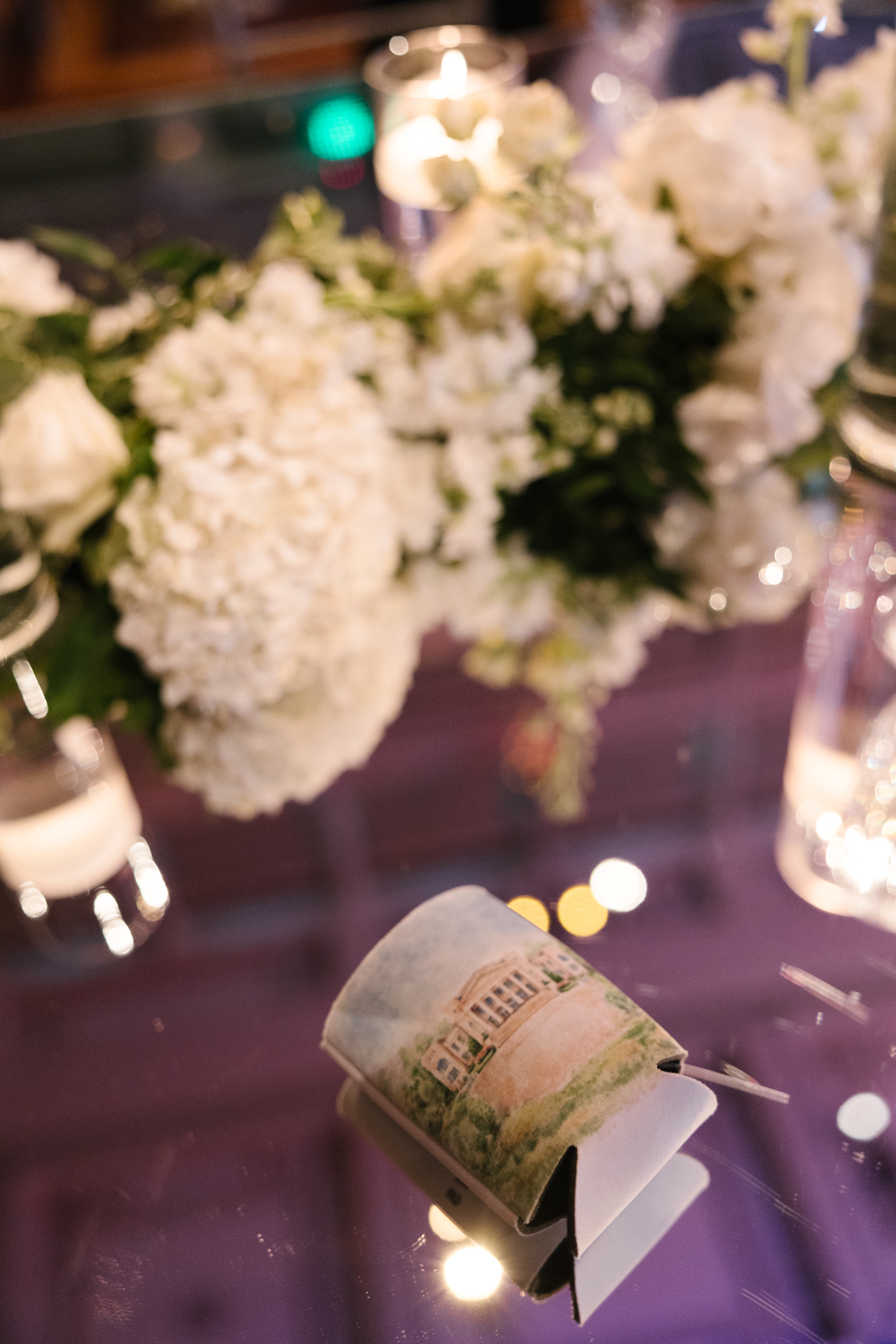 Custom koozie and florals on top of table. 