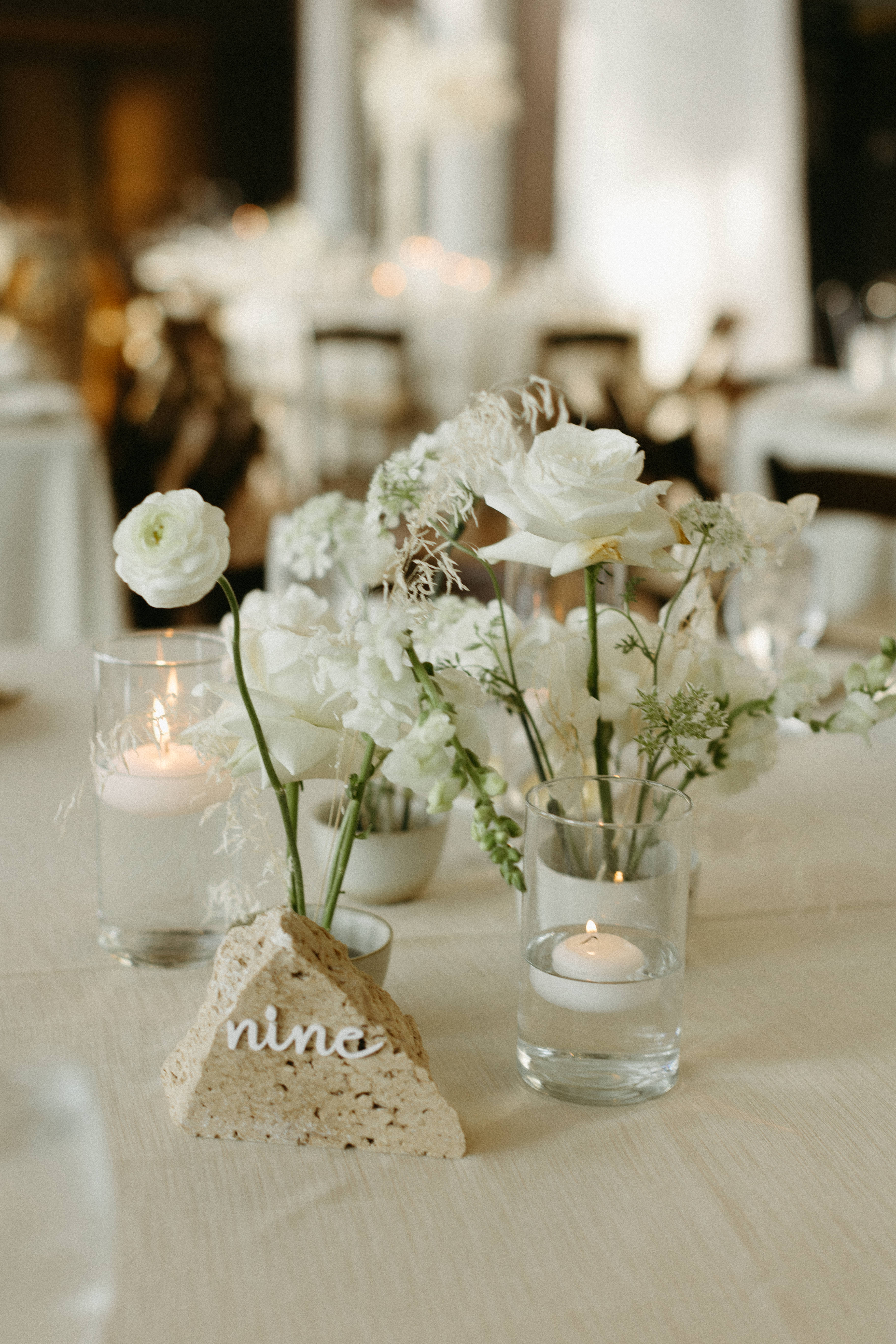 Stone table number atop formal tablescape with white florals and lined.