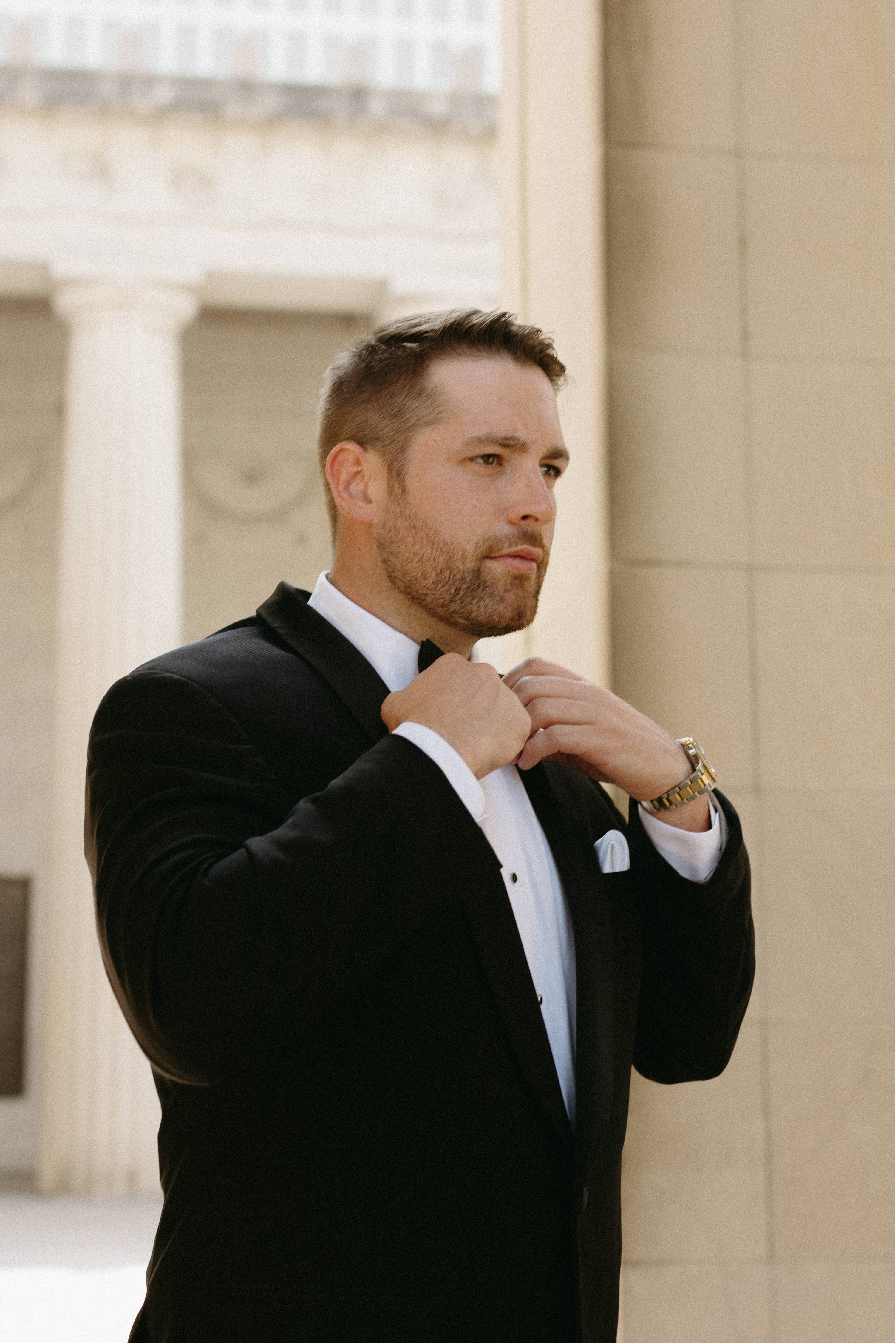 Groom fixing the collar of his tux. 