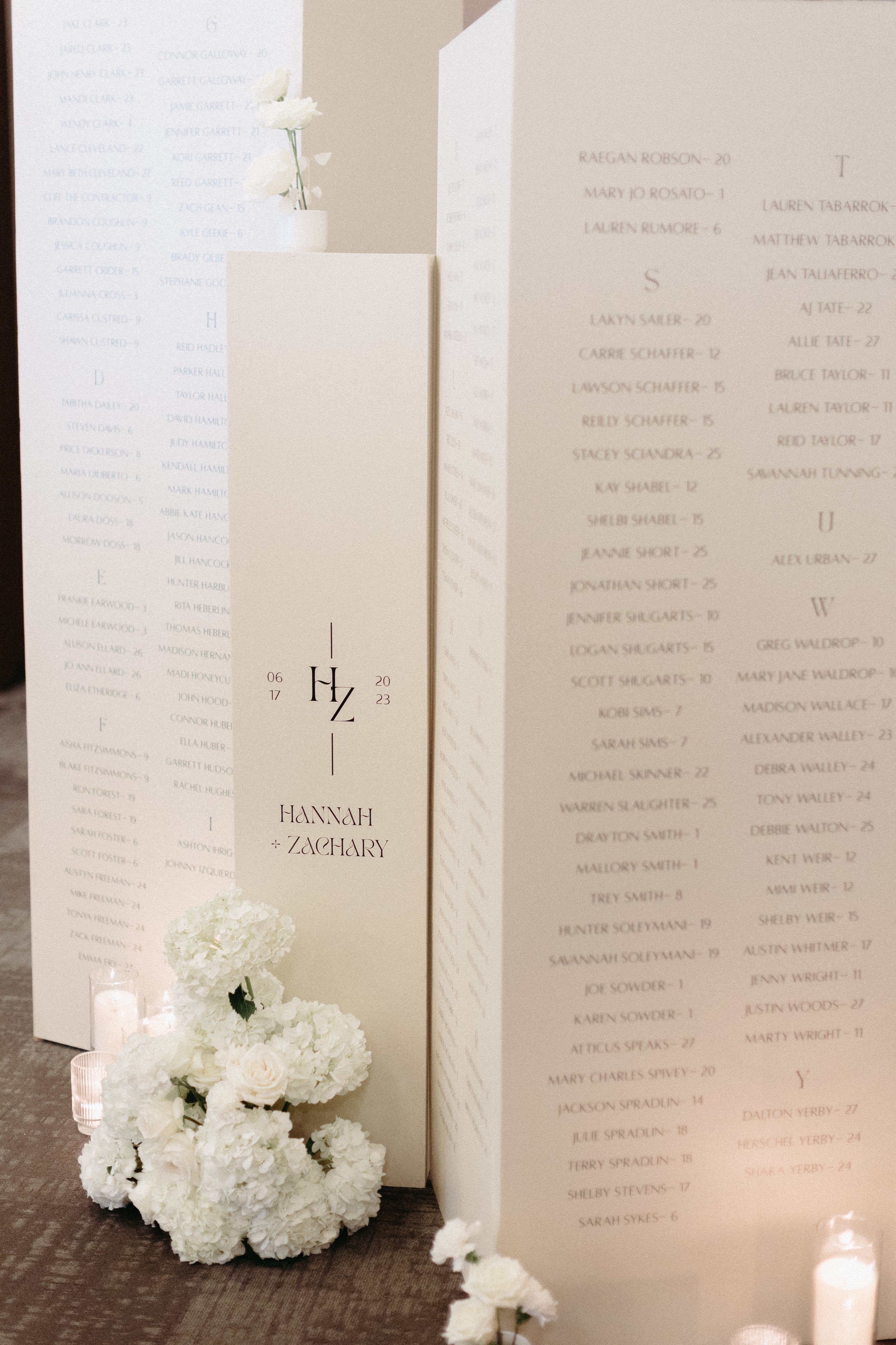 White seating chart columns styled with white candles and white florals.