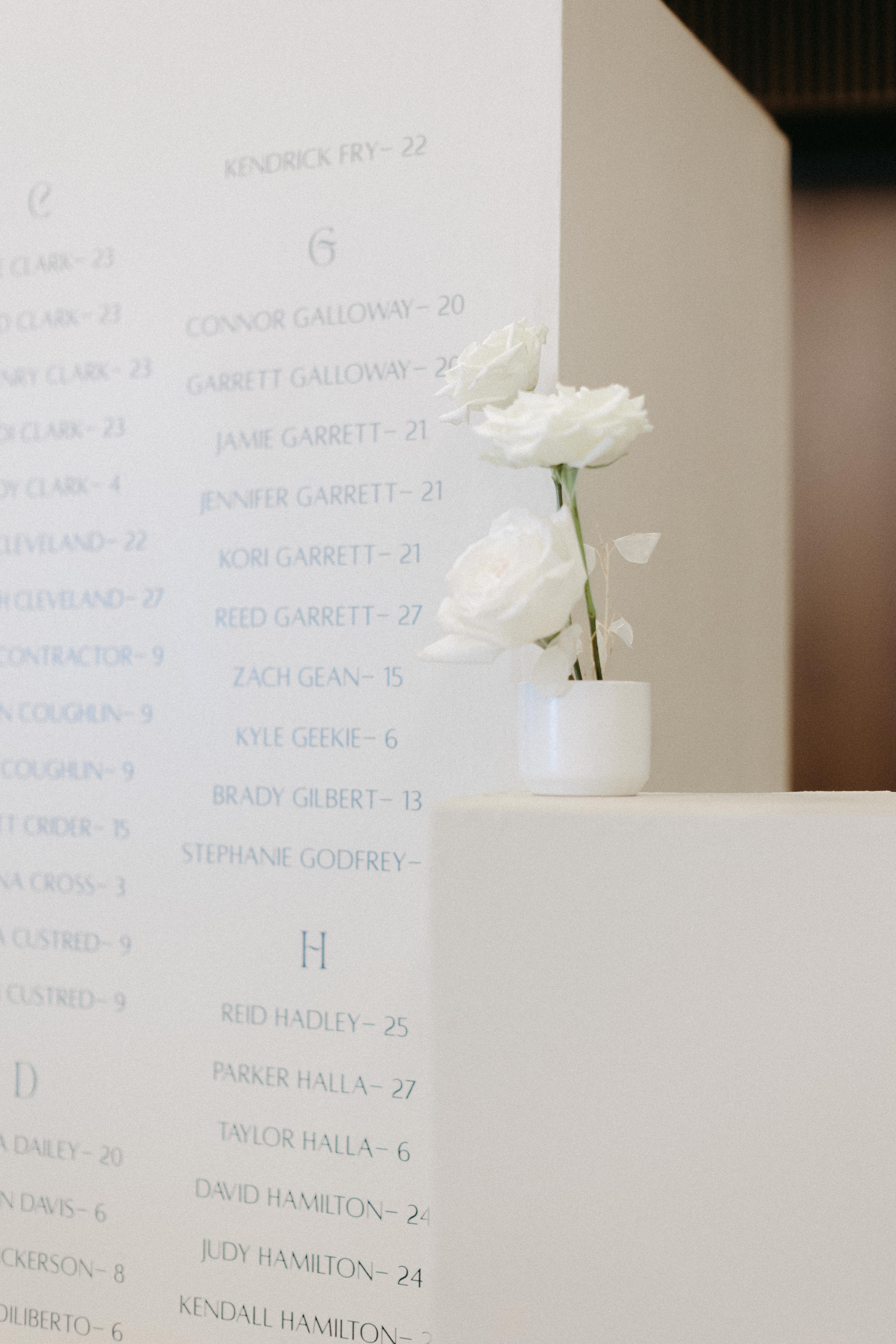 White seating chart columns styled with white candles and white florals.