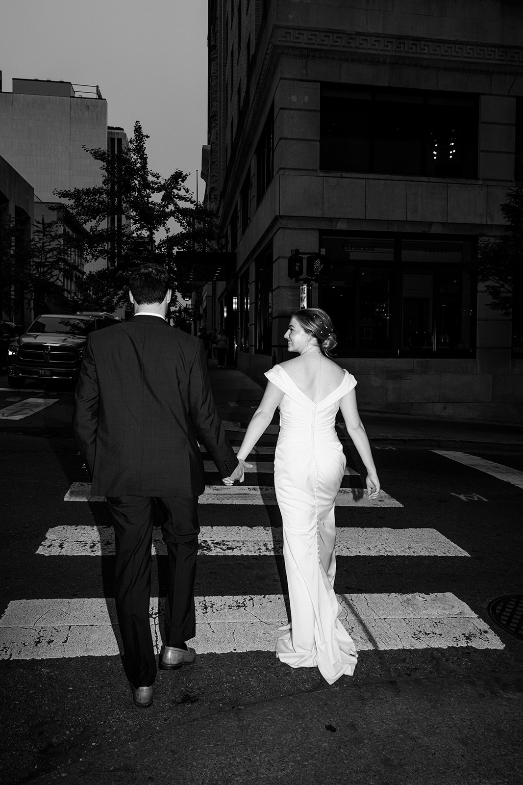 Bride and groom walking away together crossing the street.
