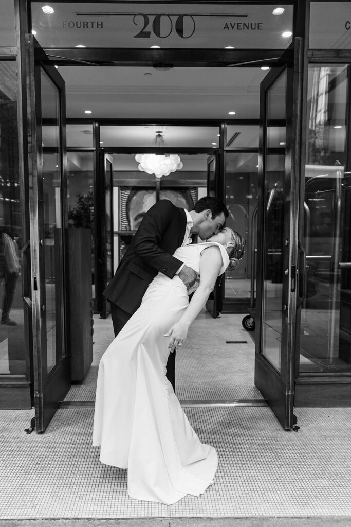 Bride and groom embrace in a kiss at doorway entrance.
