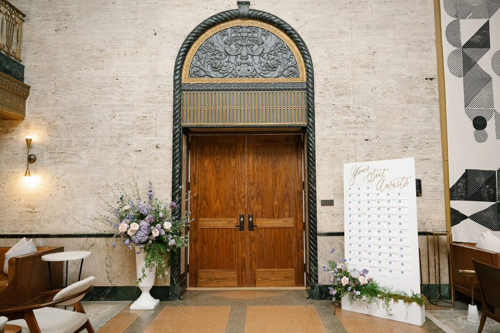 Grand arched entrance flanked by florals and escort card display.