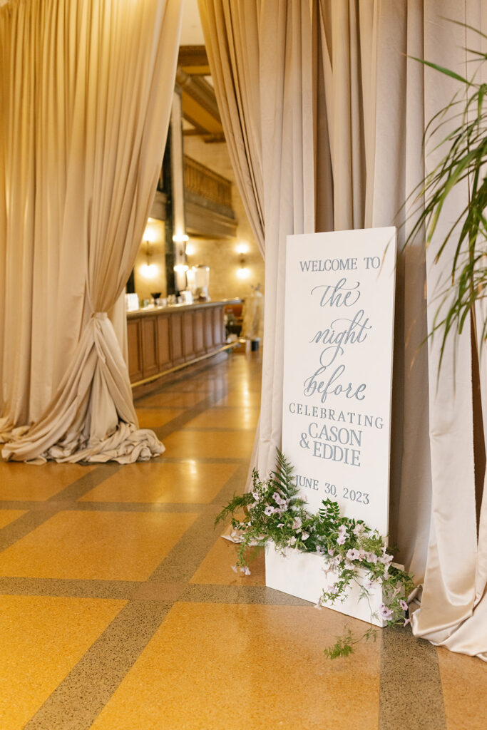 Custom Welcome Sign in front of draped entrance and ornamented with florals
