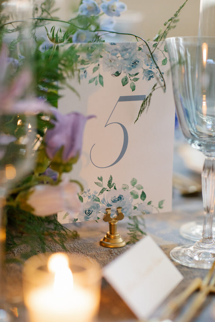 Florals, champagne flute and custom table number display on a formal dining table.