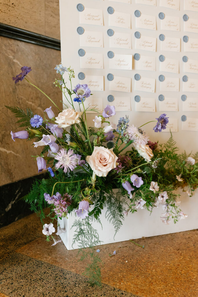 Florals ornamenting a standing escort card display.