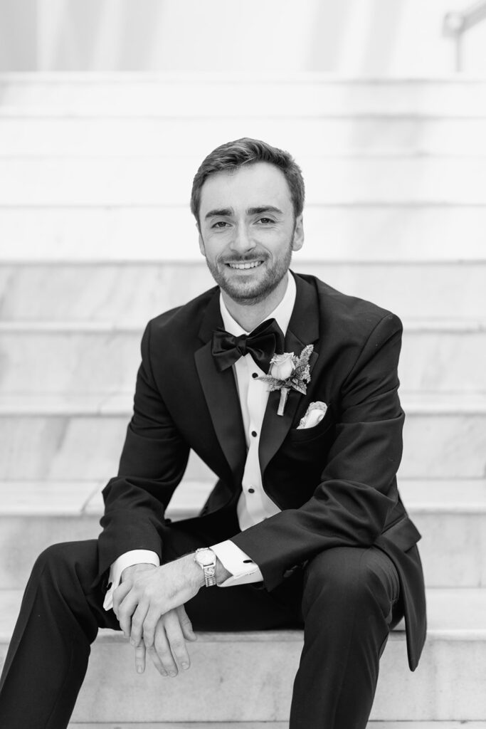 Smiling Groom sitting on stairs.