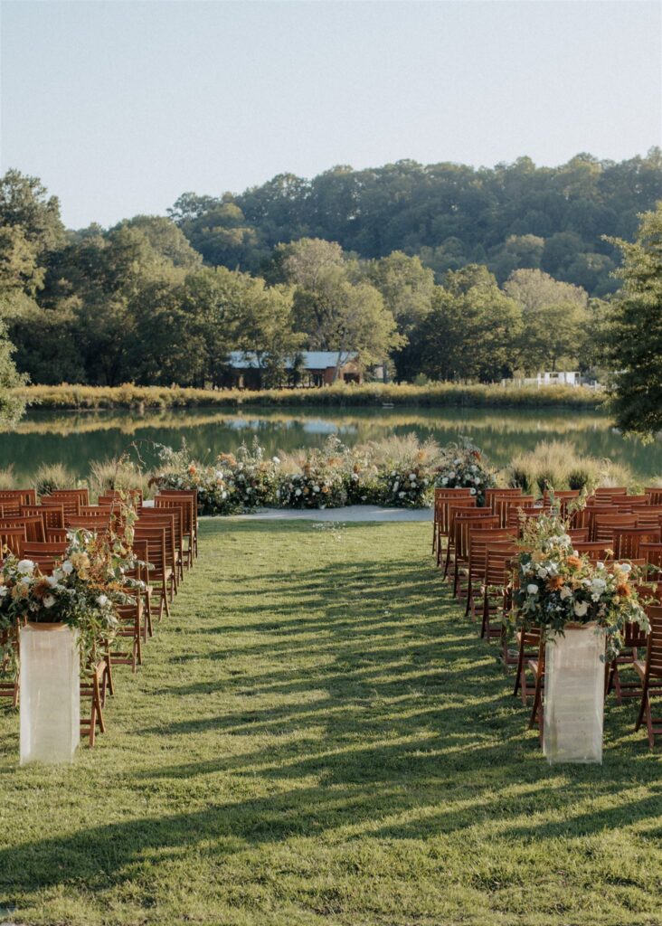 Outdoor wedding ceremony grass lawn overlooking a lake.