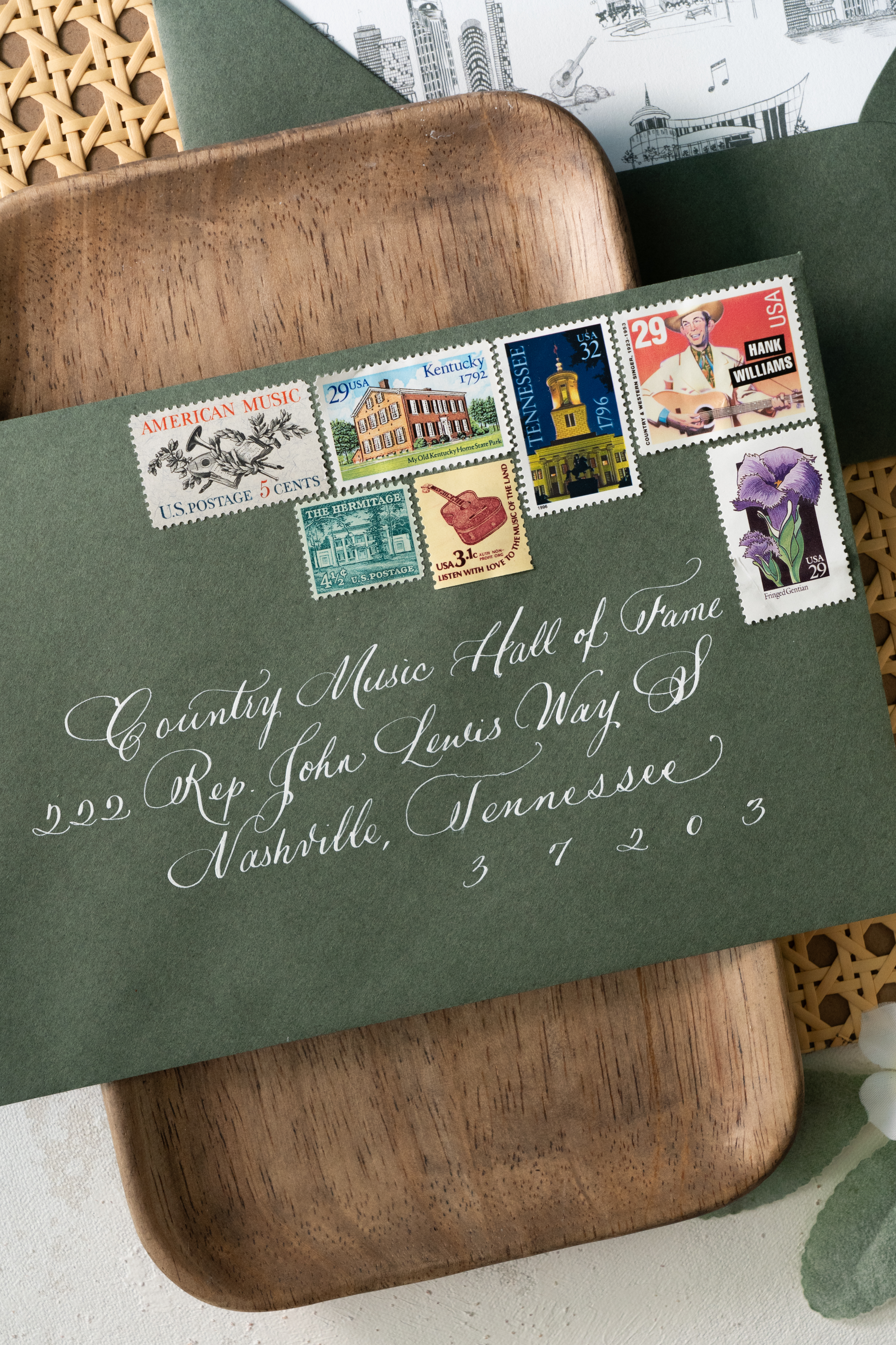 Custom calligraphed envelope with vintage postage and sitting on top of wooden tray.