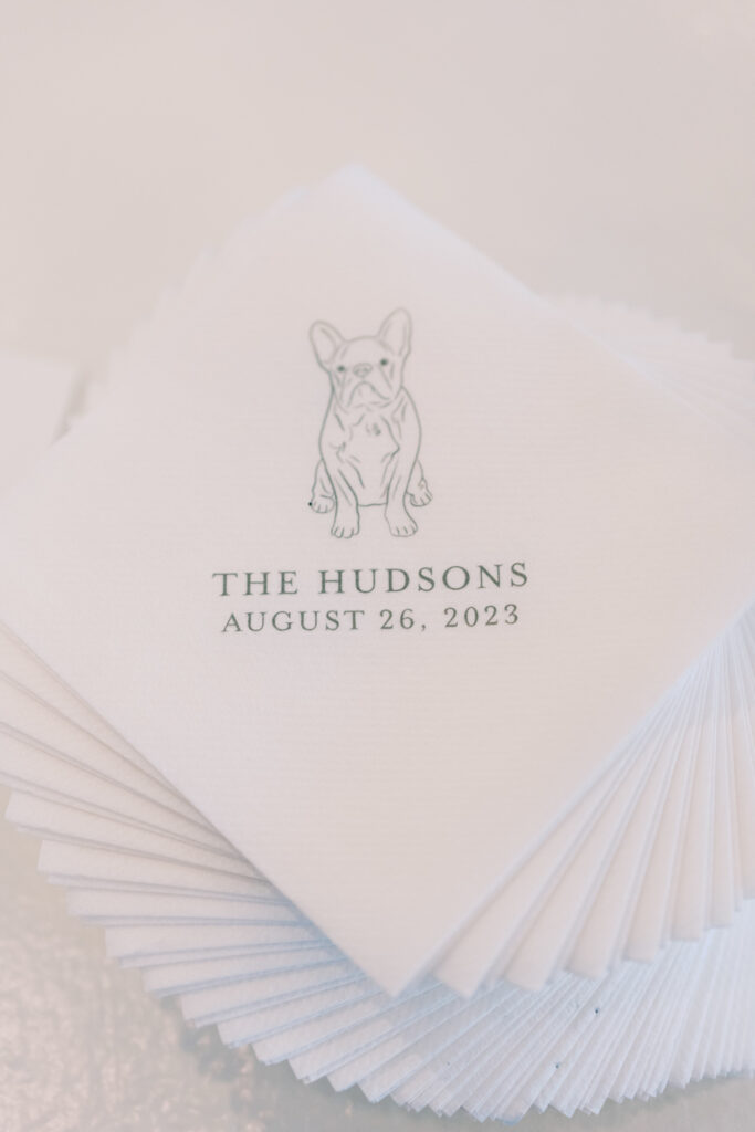 Stack of custom cocktail napkins with print of dog and wedding details.