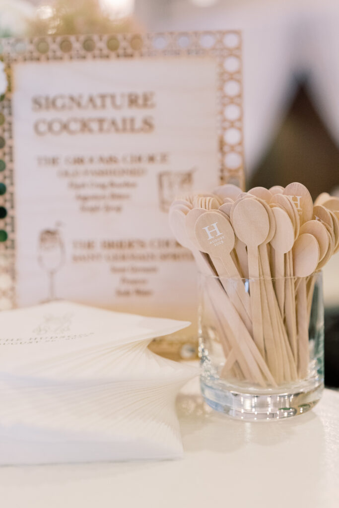 Table displaying custom cocktail napkins, laser-cut drink sign, and custom drink stirrers.