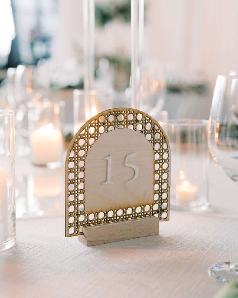 Wooden, laser-cut table number sign on table with candles.