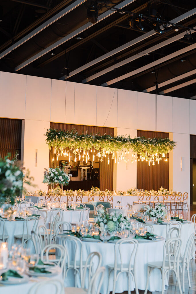 Formal wedding reception venue set up with formal table set ups and hanging floral chandelier.