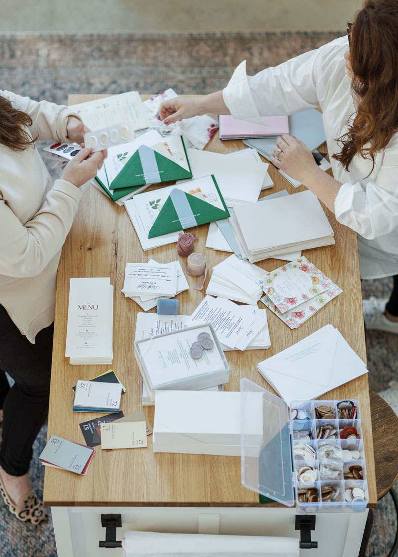 Action shot of production and delivery on a work table showing White Ink Calligraphy & Co's high-touch custom stationery and wedding invitation services.