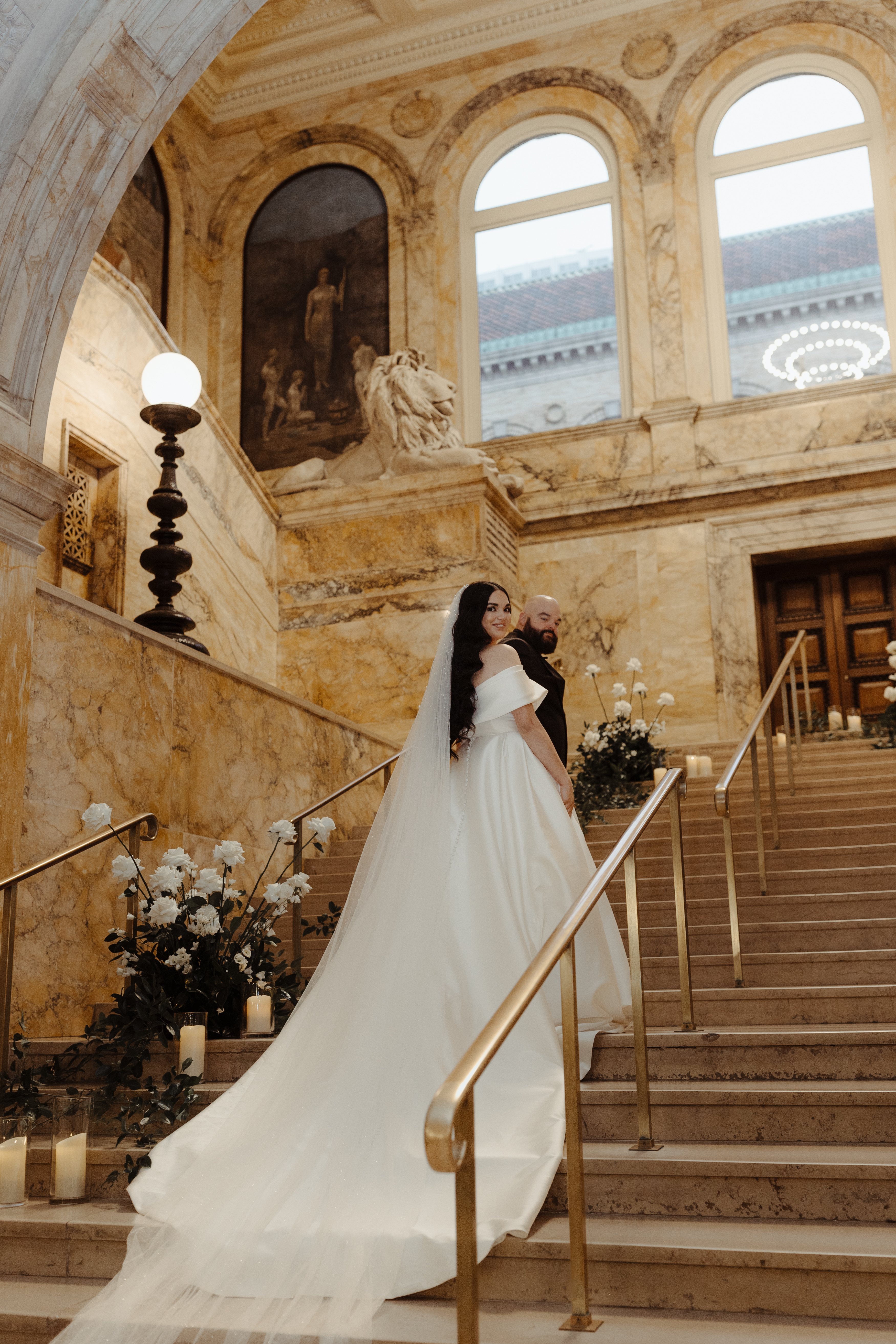 Bride and groom walking up staircase looking back at camera