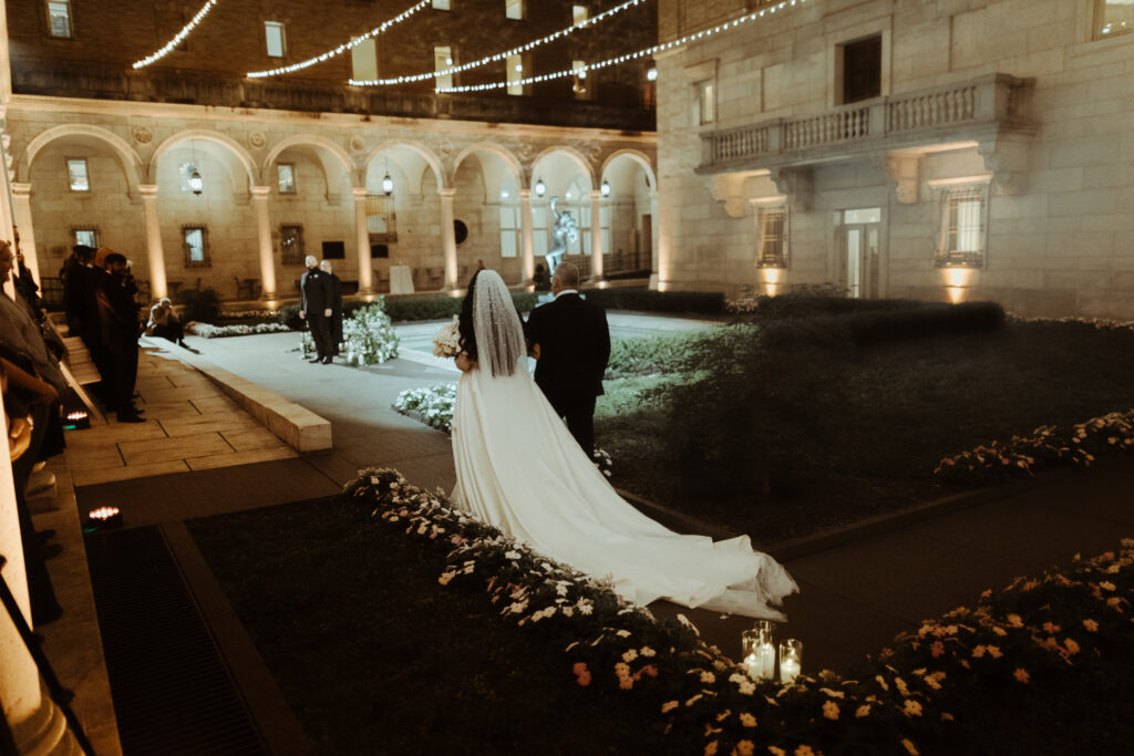 Bride walking down aisle in nighttime outdoor venue