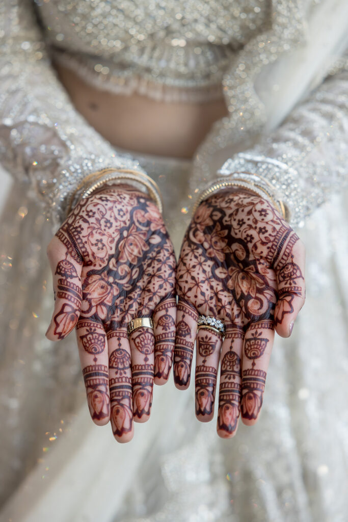 A bride with palms opened outward displaying Mendhi.