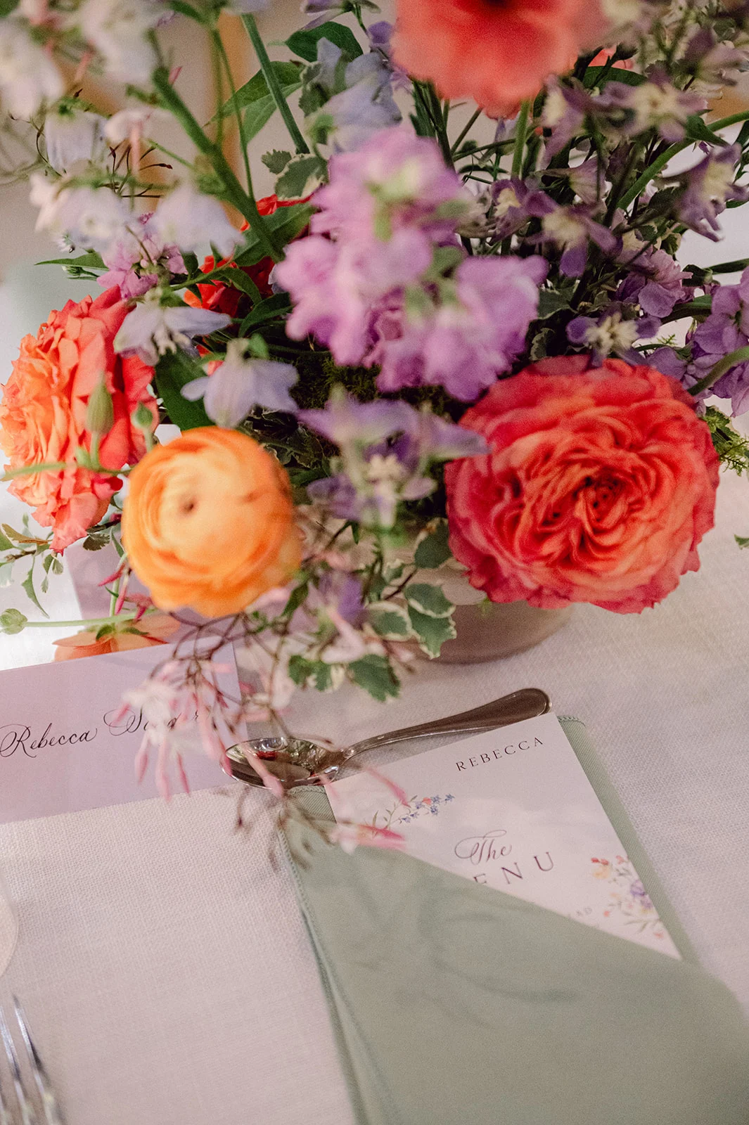 custom menus peeking out of sage green napkin