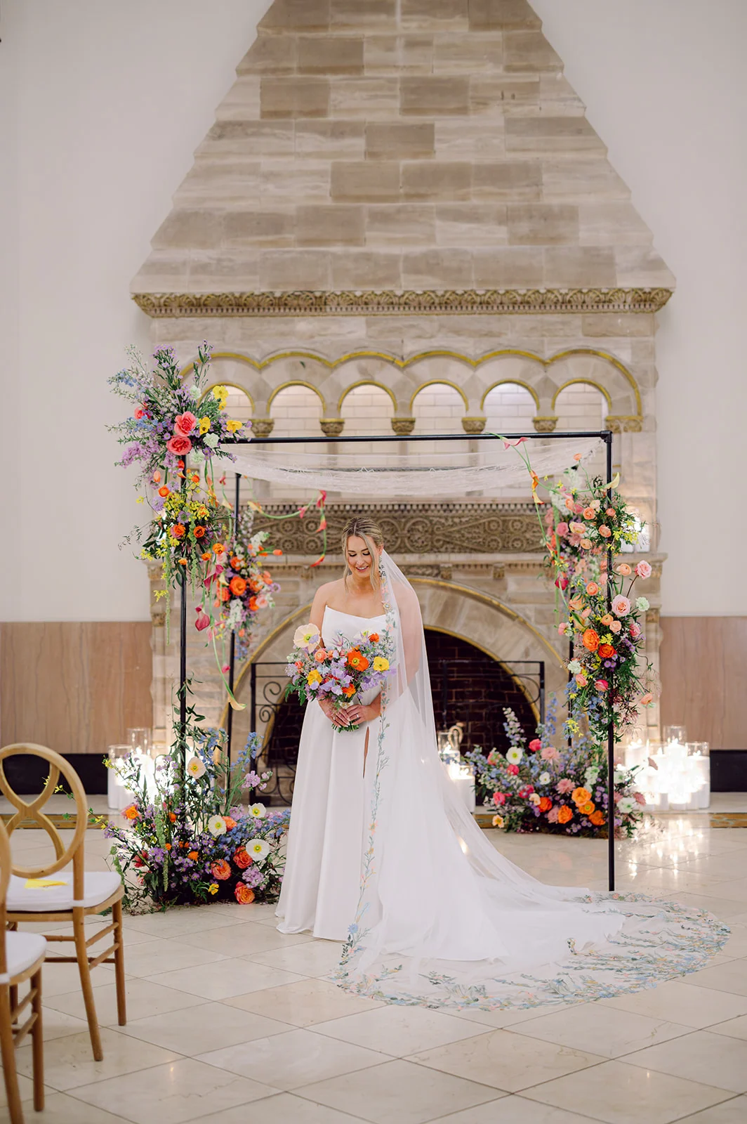 bride in wedding gown with stunning veil surrounded by colorful florals featuring lavender.