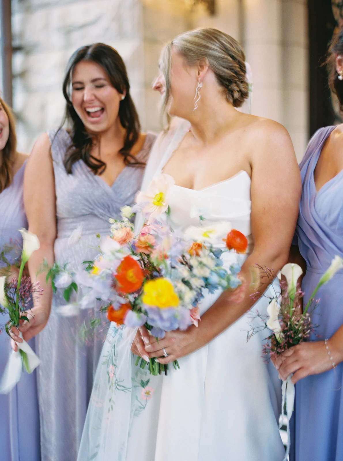 bridesmaids in lavender dresses surround bride.
