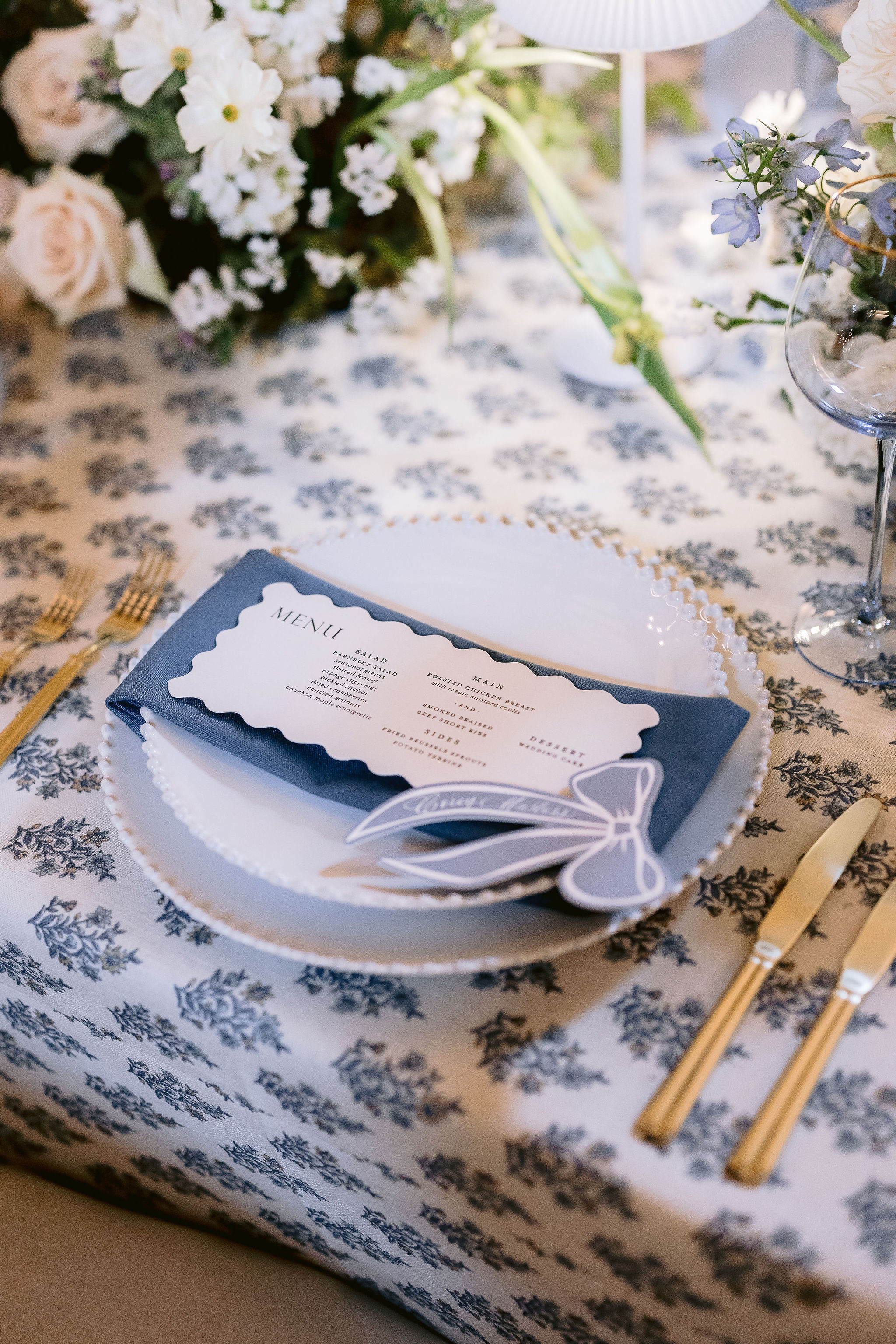 blue ribbon place cards sit on custom die-cut menu on top of white plates and napkins.