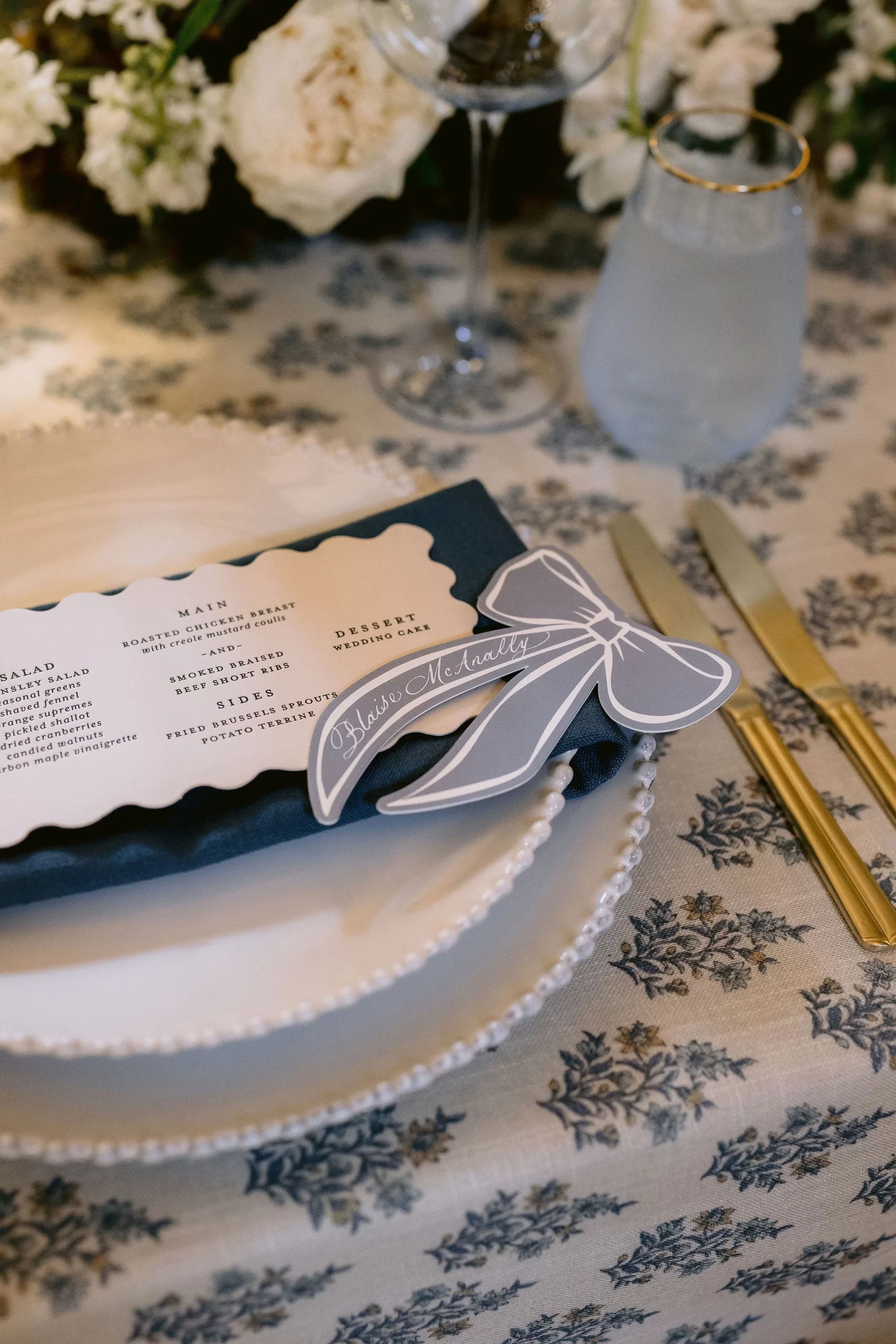 blue ribbon place cards sit on custom die-cut menu on top of white plates and napkins. 
