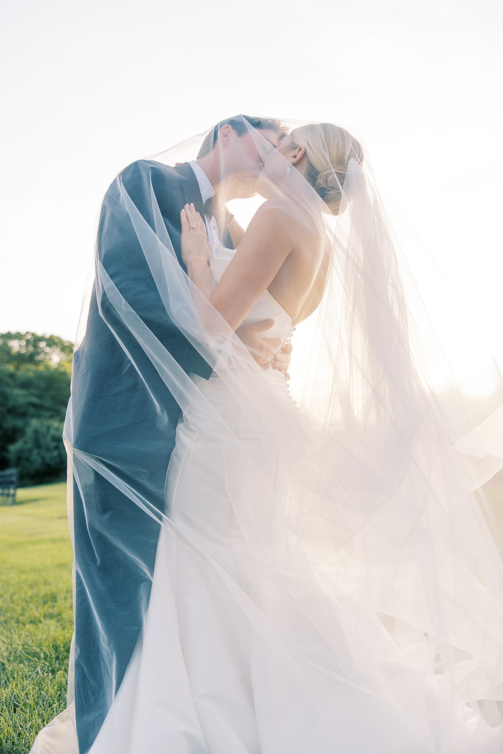 romantic newlywed photo of couple kissing under bride's veil 