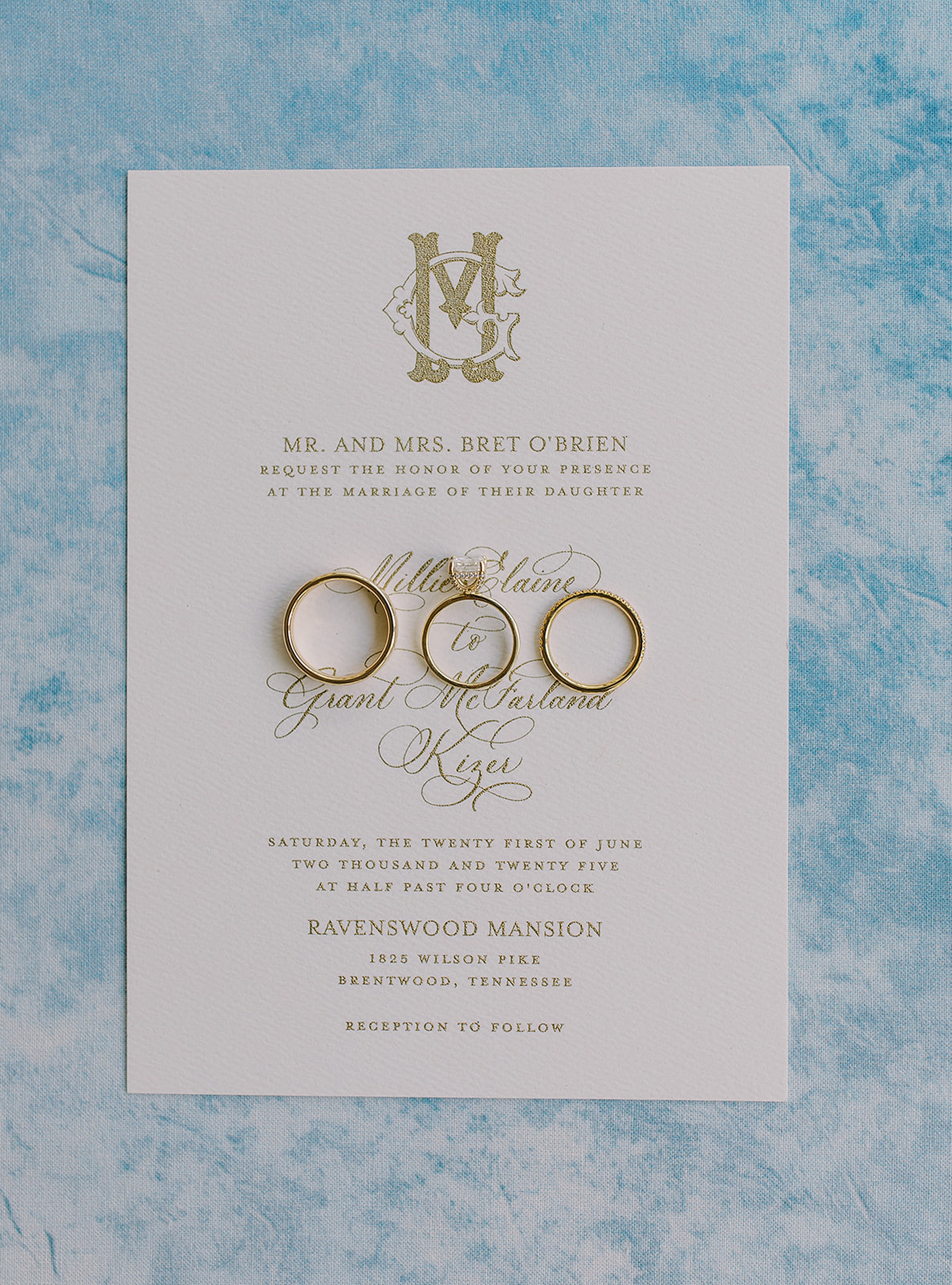 wedding rings on white invitation with gold calligraphy 
