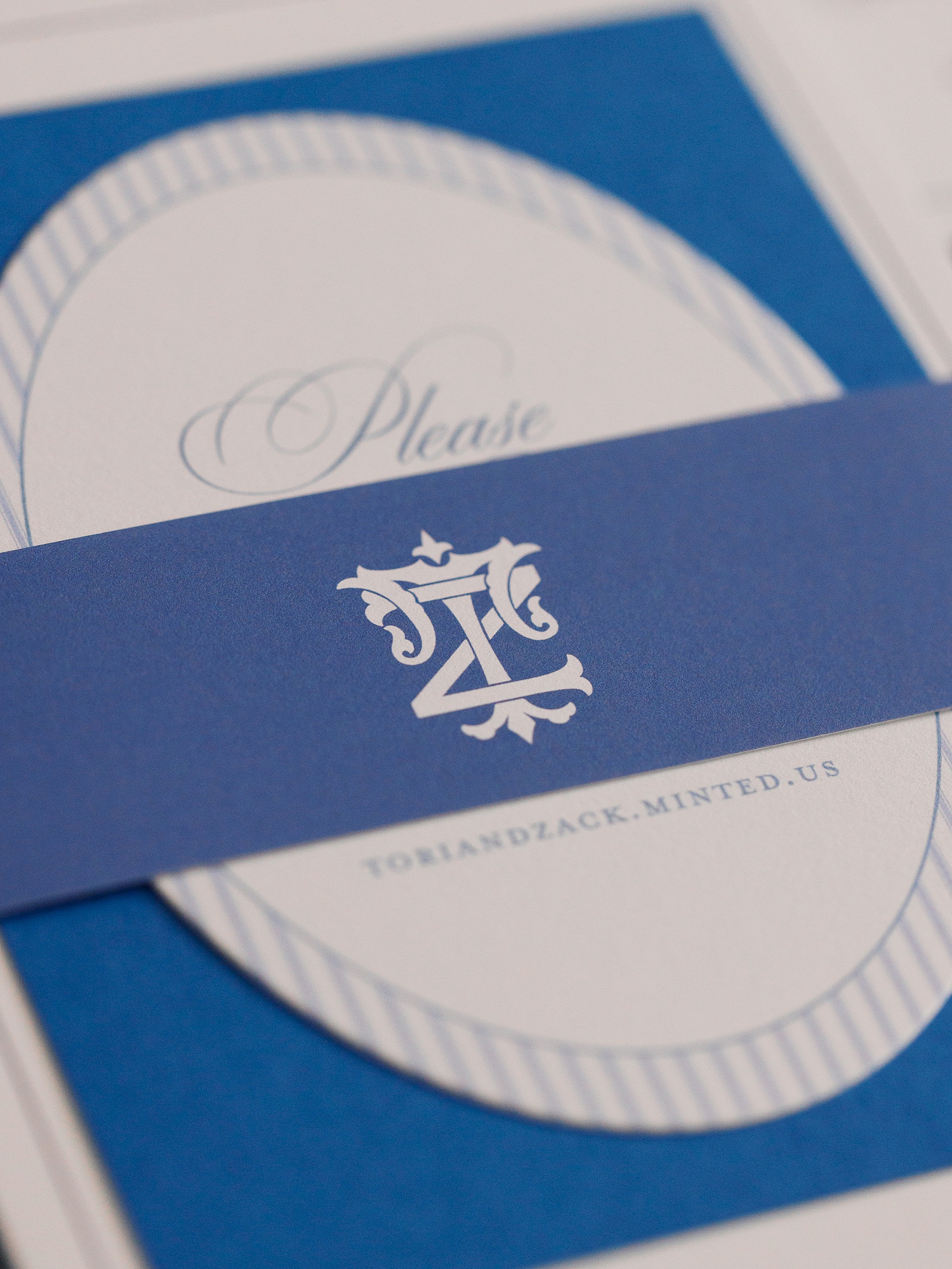 blue wedding invitation featuring belly band with custom monogram