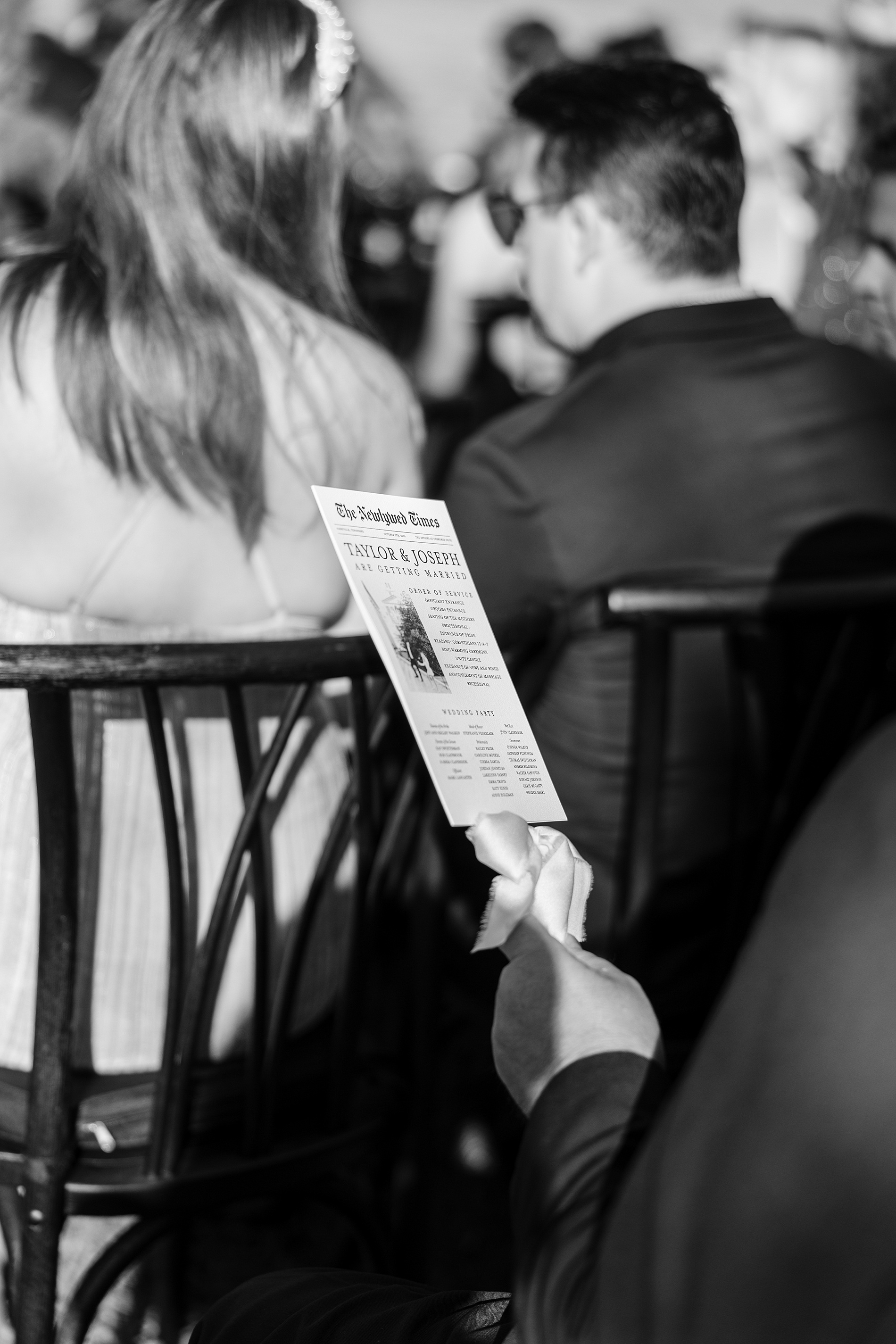 guests holding newspaper styled fan that doubled as a program and wedding timeline