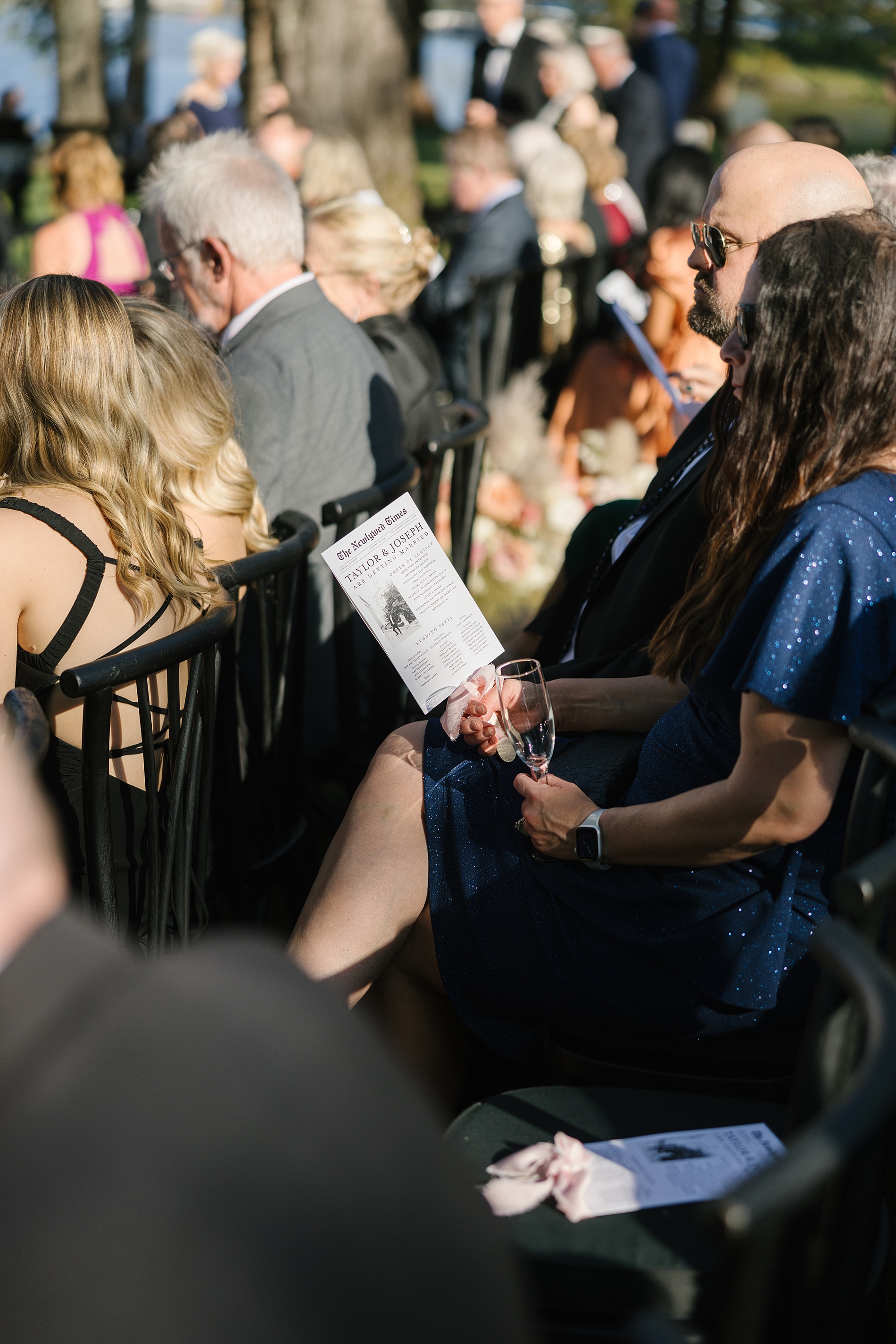 guests holding newspaper styled fan that doubled as a program and wedding timeline