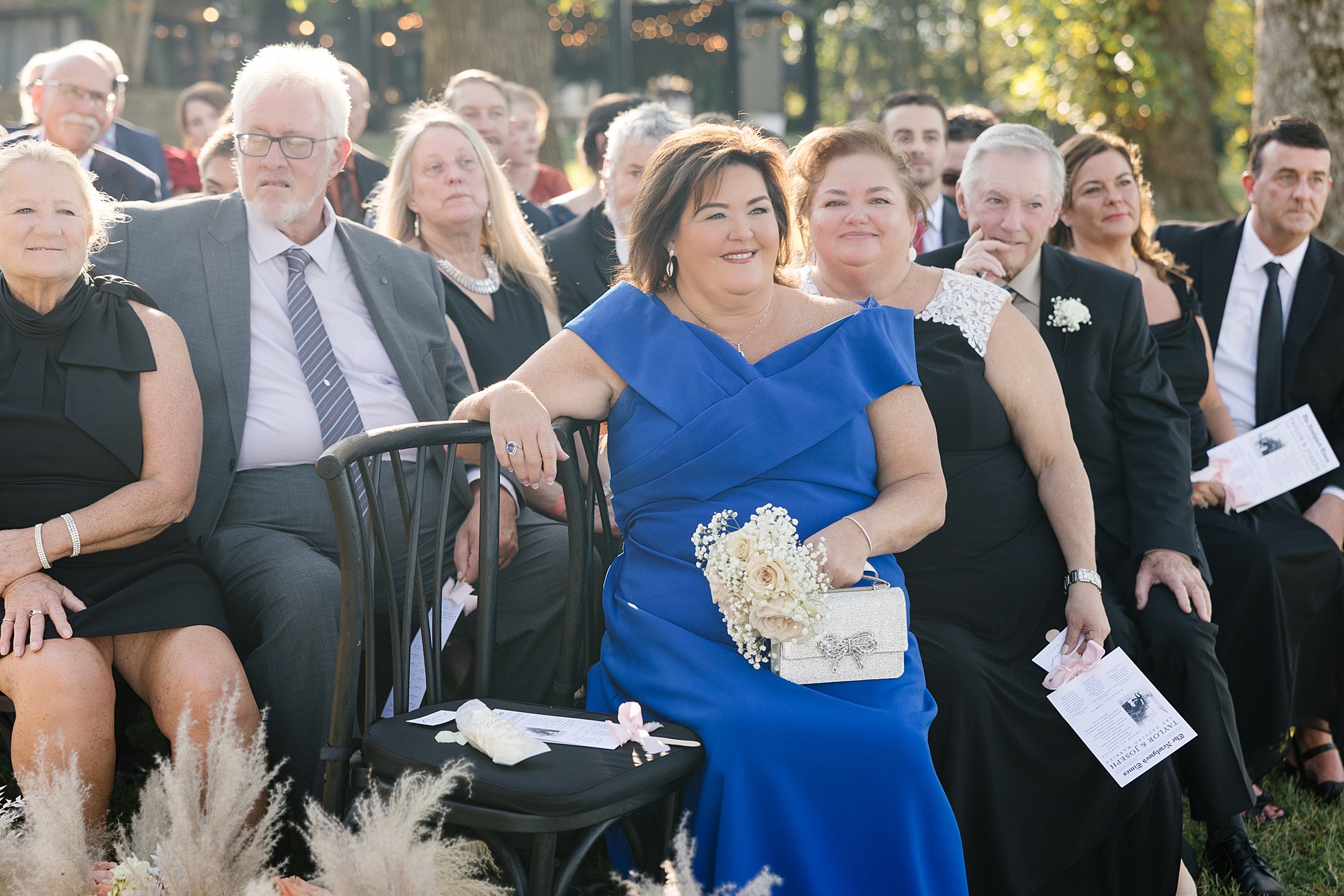 guests at wedding ceremony holding newspaper styled fan that doubled as a program and wedding timeline