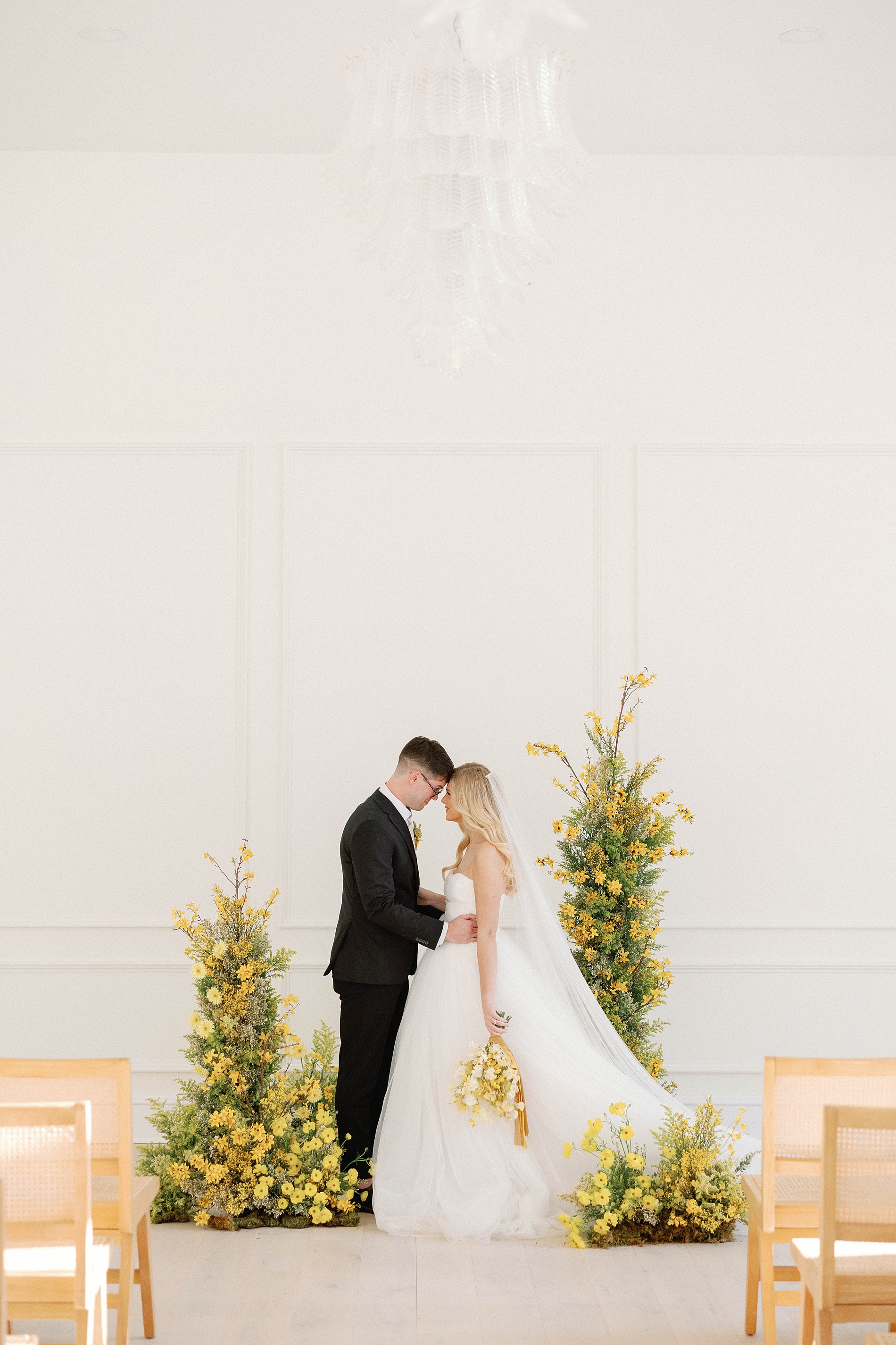 bride and groom photos at wedding ceremony surrounded by yellow flower displays 
