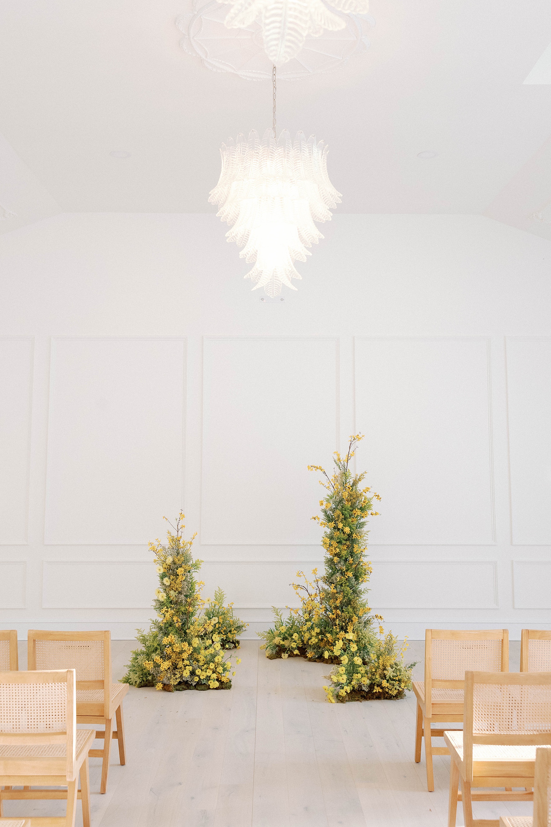 yellow flower displays with ample greenery decorate wedding ceremony space